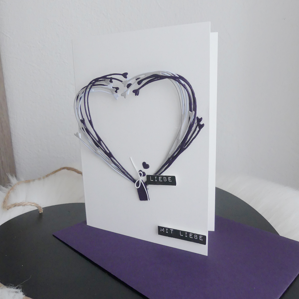 Designbeispiel Kartenrohling verziert mit weiß-lilafarbigen ausgestanzten Ranken gebogen zu Herz