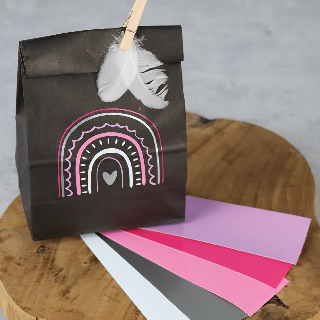Designbeispiel Ritrama Optima auf Geschenktütchen dekoriert mit weißen Dekofedern und Farbstreifen